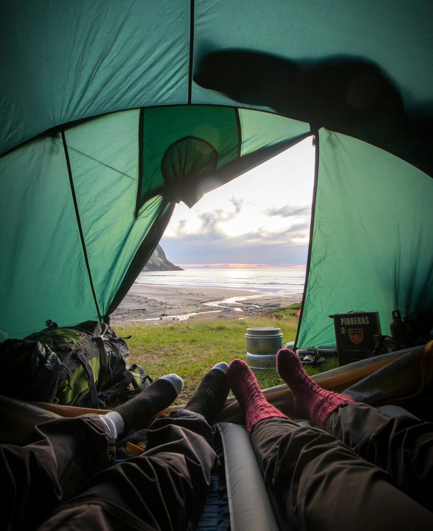 tältat nära strandkanten på lofoten, foto taget inifrån tältet och man ser våra fötter i tältöppningen